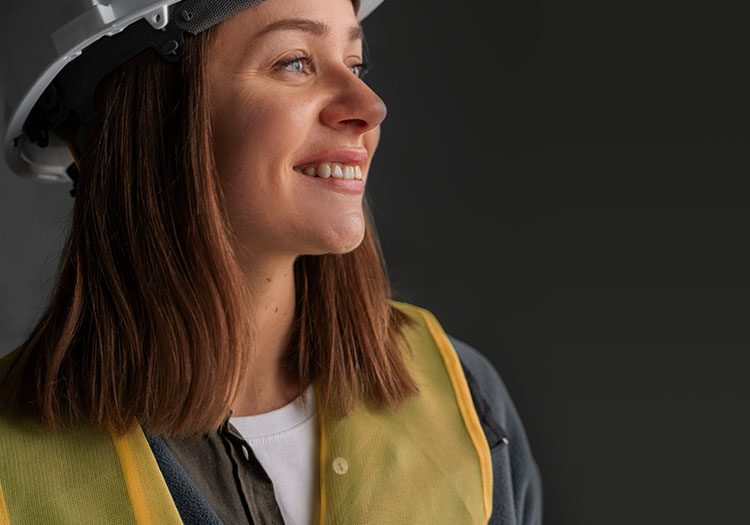 Woman engineer smiling with helmet at high vis vest